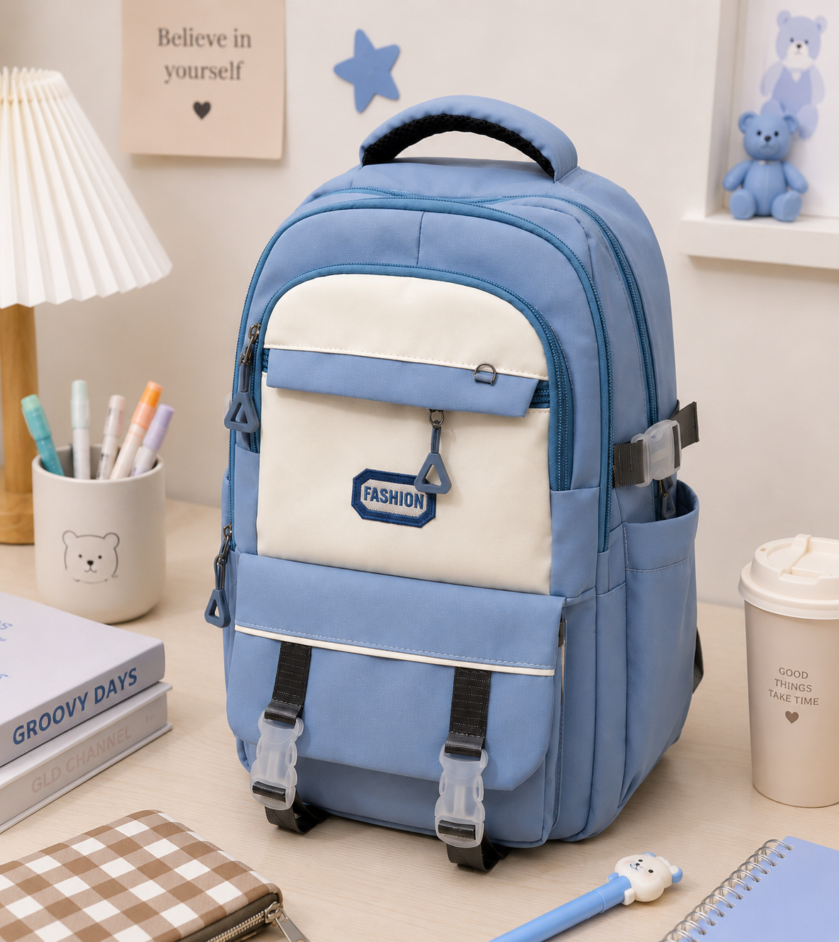 A light blue and cream backpack with multiple zippered compartments and side pockets, styled on a desk next to a lamp, notebook, and coffee cup.